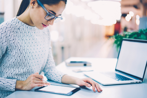 Women using a graphic tablet sitting next to her laptop.